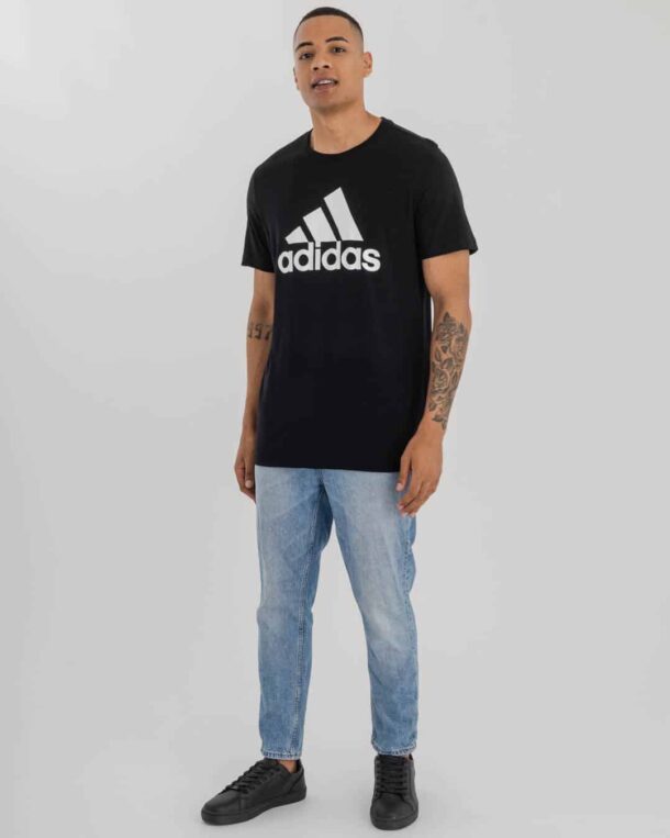 man wearing light blue denim & black Adidas t-shirt Adidas logo on chest