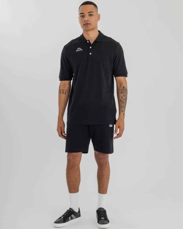 man wearing Black Kappa Golfer with Kappa Logo on right side & Black shorts.