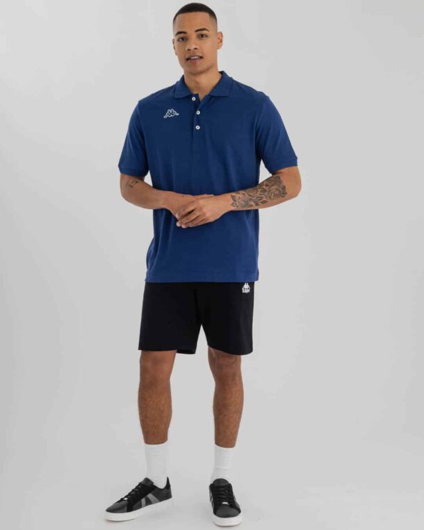 Full length of man wearing navy blue Kappa Golfer with omini logo on right and black shorts