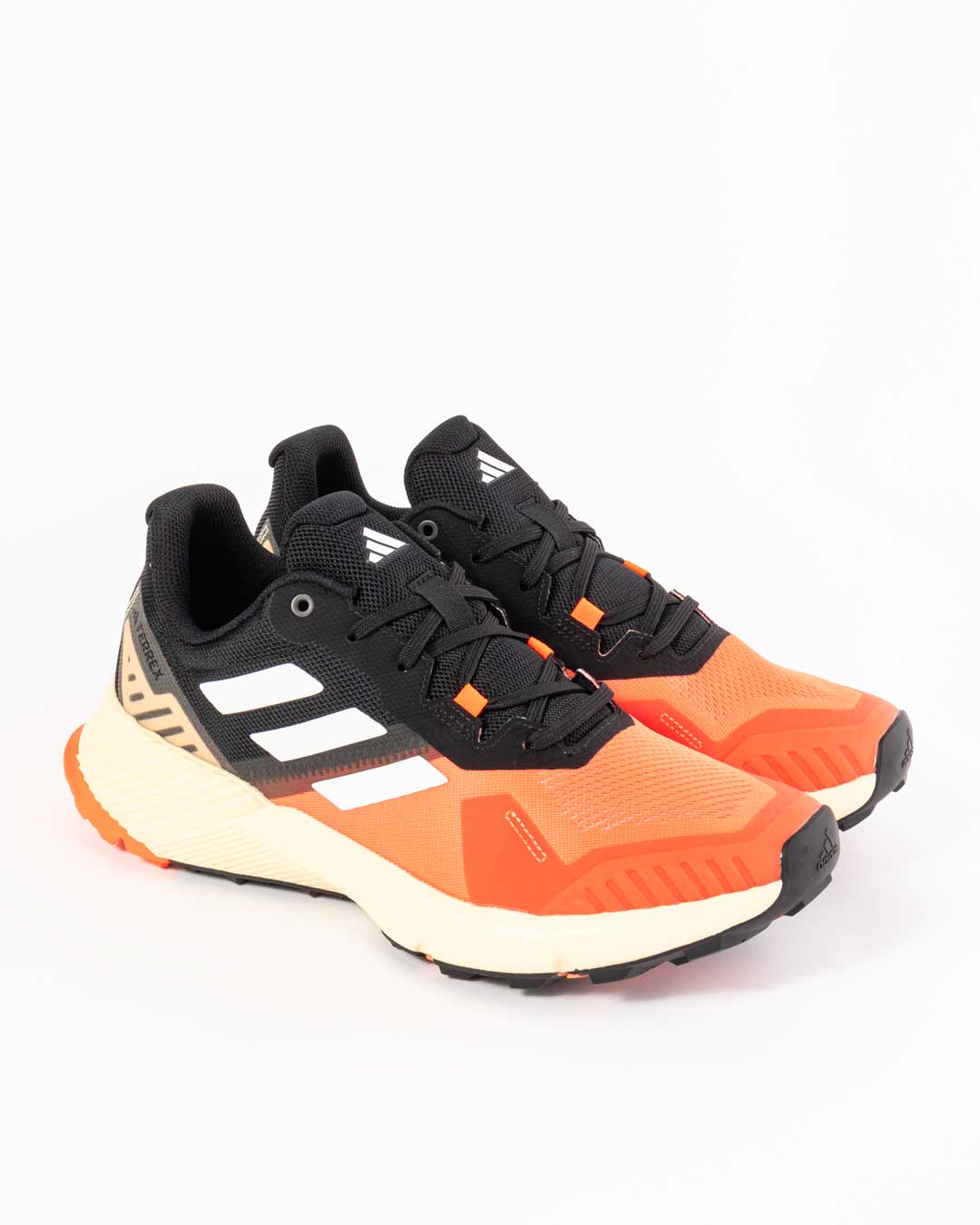 side angled shot of men's adidas trainers in orange and black paneling with cream midsole. Three stripes in white on upper and adidas logo embossed on toe cap.