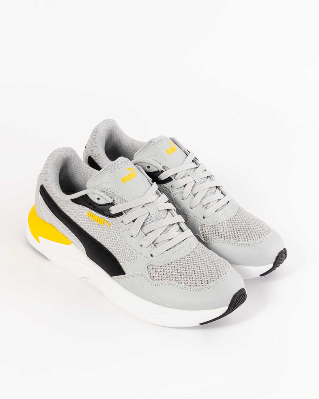 side angled shot of children's Puma sneakers in grey with black paneling on upper, yellow paneling on heel, black paneling towards first set of eyelets